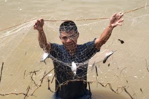 Man holding up a net with caught fish