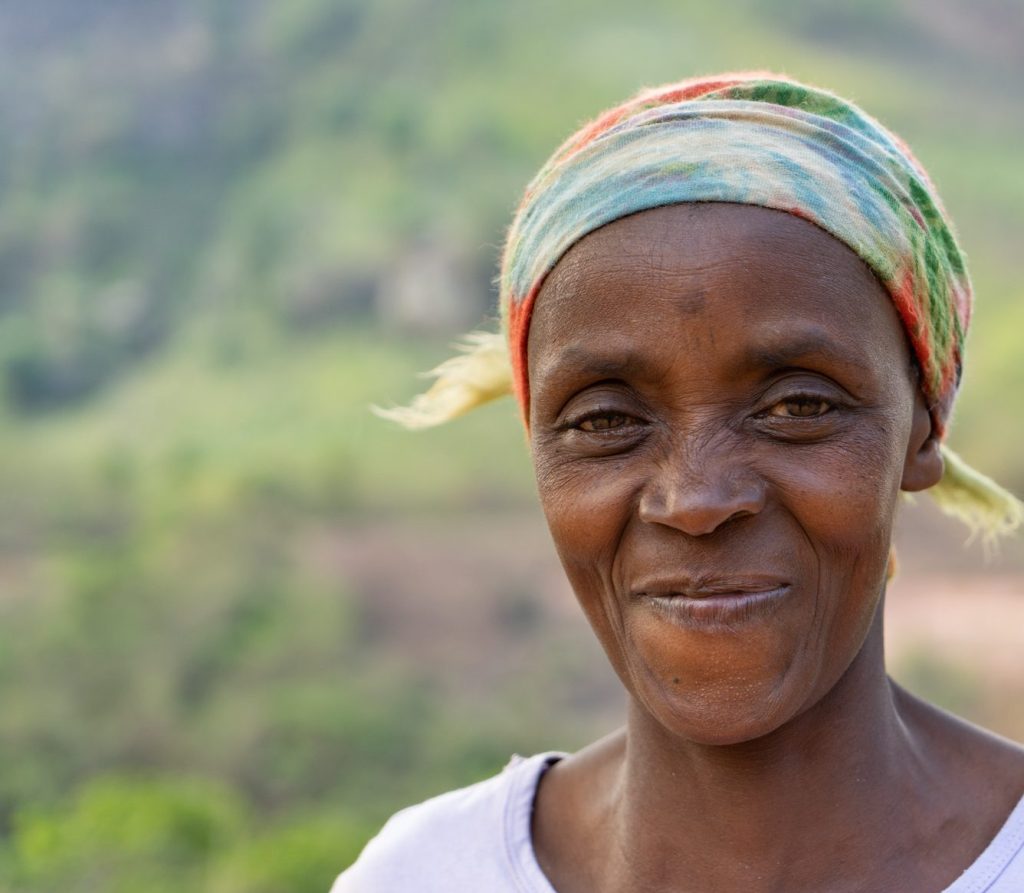 A portrait of a smiling woman facing the camera, wearing a colourful headscarf.