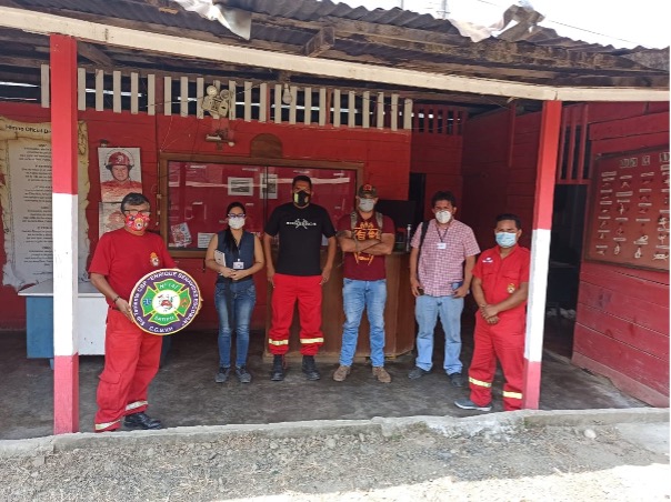 Six people stand in front of a project board about rainforest fires. One is holding a plaque. 