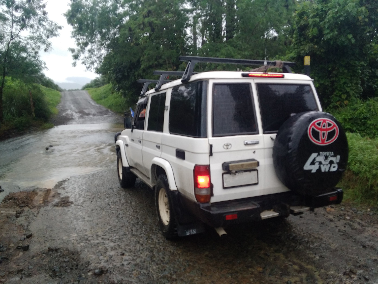 An image of a white land rover crossing a flooded road.