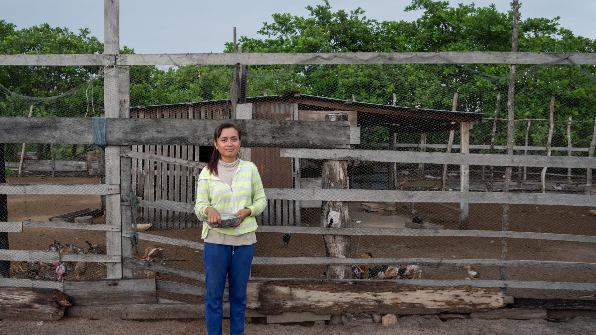 Chann Phearum standing in front of a chicken pen