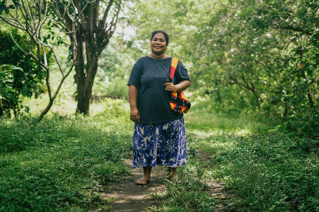 Agnes stands on a grassy path surrounded by trees.