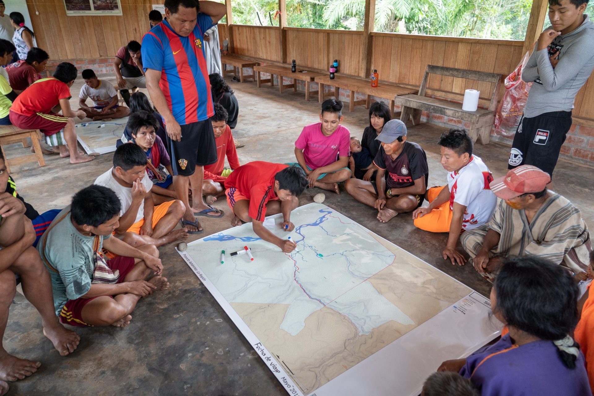 A group of people in a building surrounding a map