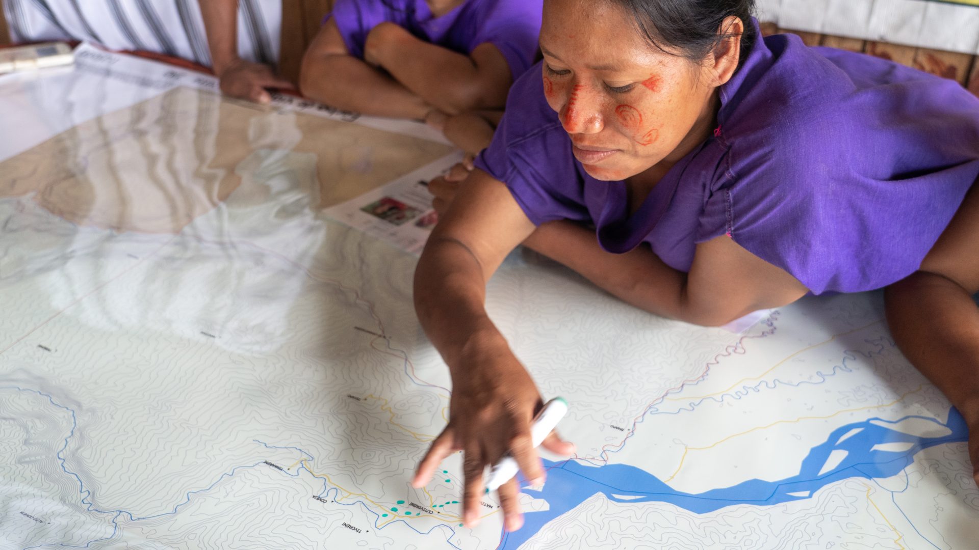 A group of people drawing details on a large printed out map of their home area.