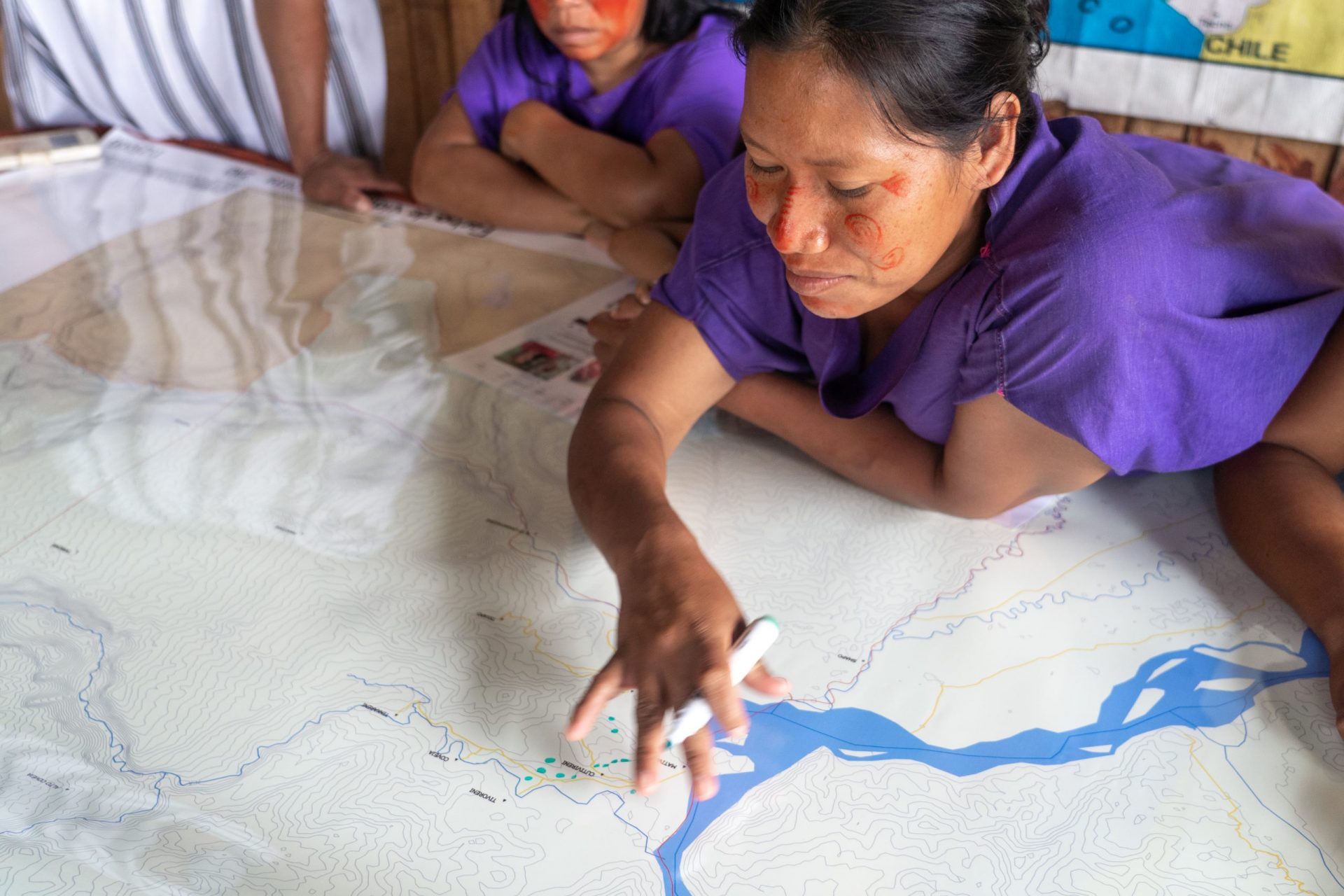 A group of people drawing details on a large printed out map of their home area.