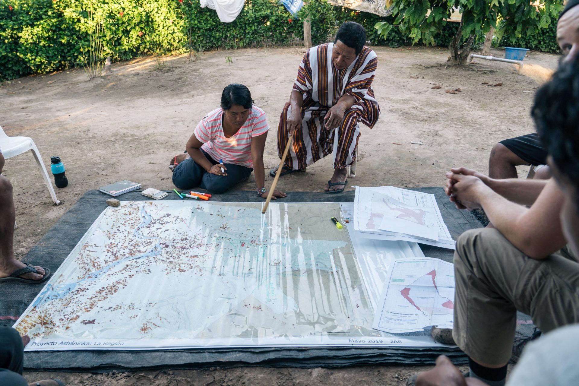 Cool Earth team members look at a large map of the area in a remote village in Peru.