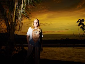 A woman stands in the rainforest at sunset