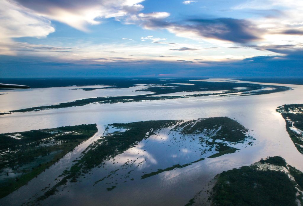 large stretch of Brazilian Amazon river , tributaries come off the main river body and there are patched of green vegetation.