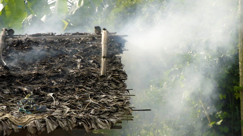 Dried leaf roof with roof with rainforest backgound and smoke rising