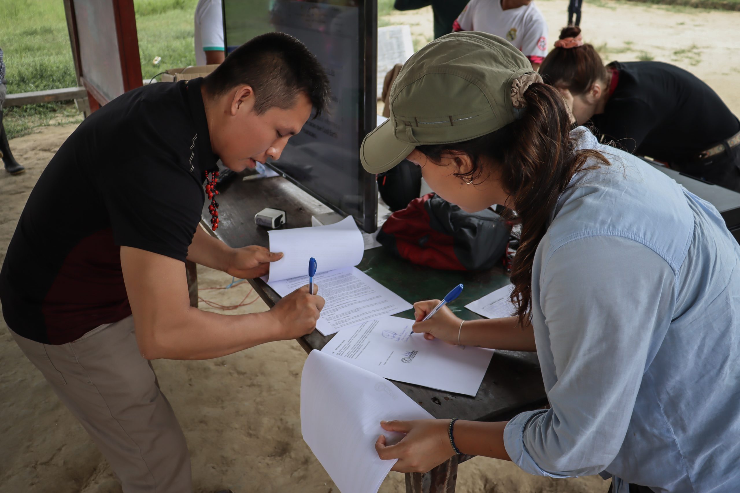 Isabel, Peru Programme Manager, and Robin, chief of Huaracayo, lean on a table and are signing the forest agreement for 2022.