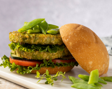 Meat-free burger, two green veggie patties topped with tomatoes and greens