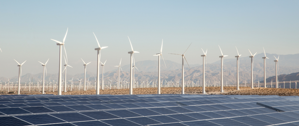 Wind turbines and solar panel farm in the Californian desert, mountains can be seen in the distance.