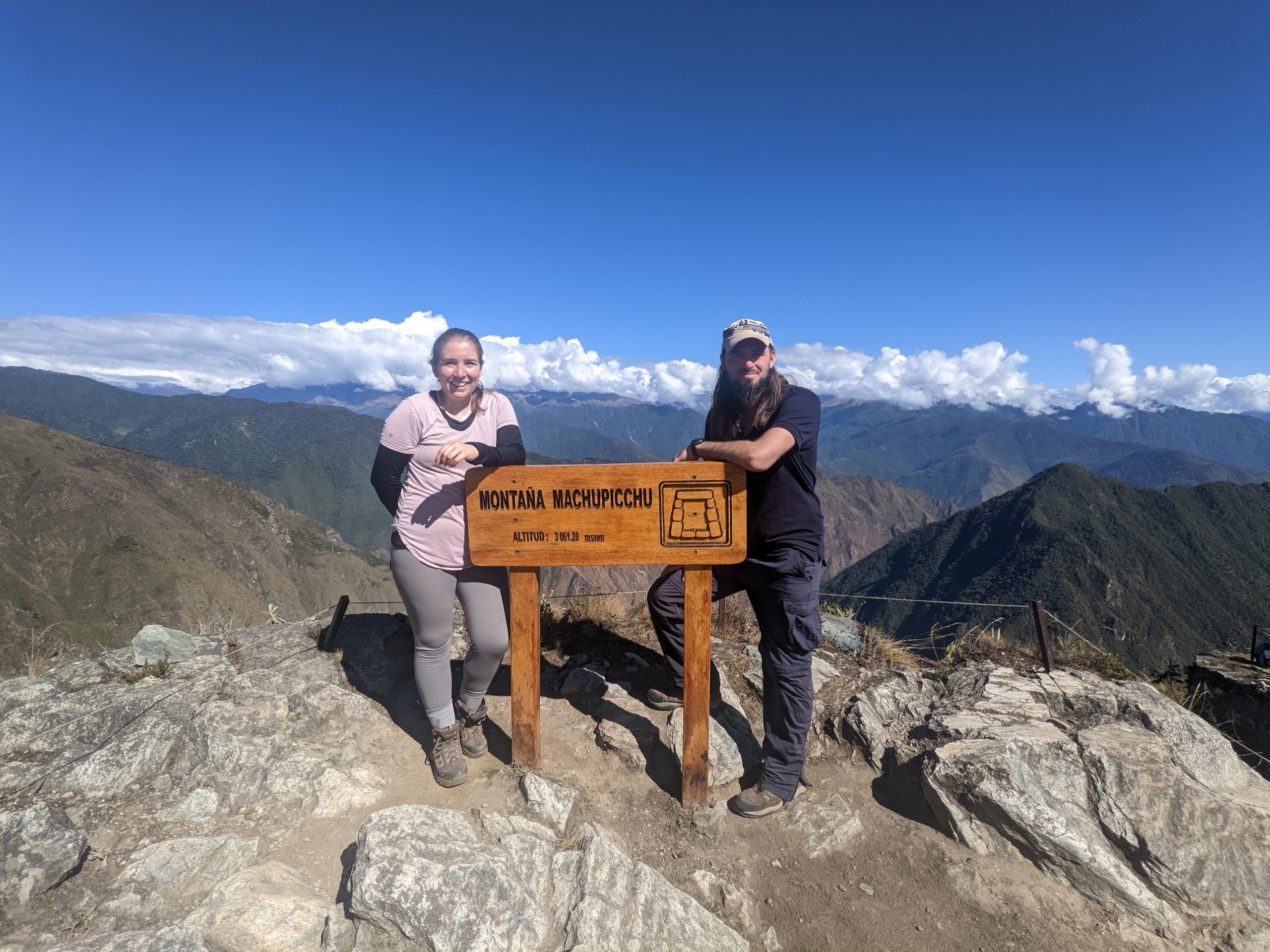 Luke and Laine stand behind the Montana Machu Picchu sign 3061.28 meters above sea level, they were walking gear and smile at the camera.