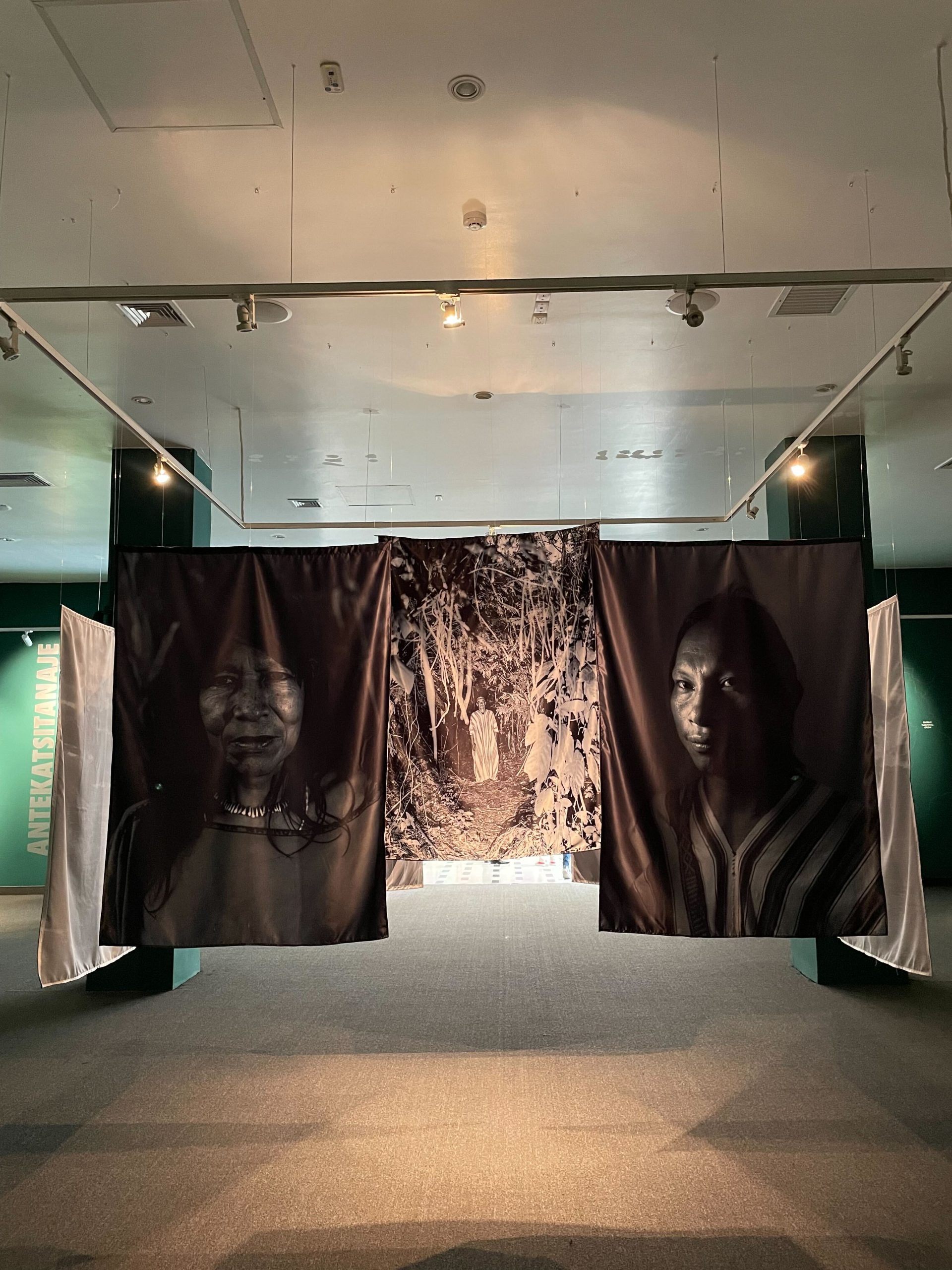 Black and white photography of Asháninka people hanging in the CARE PAMARI exhibition