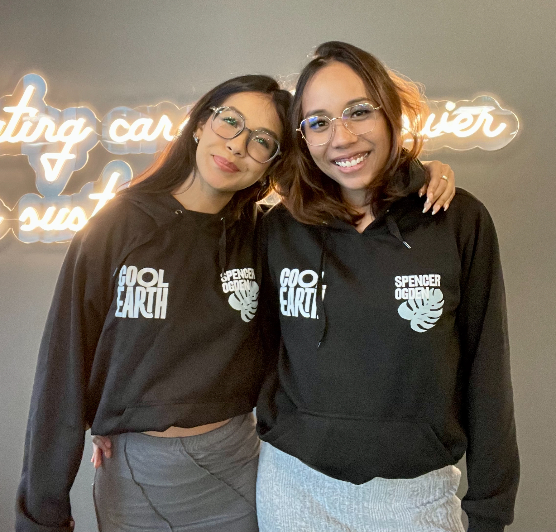 Two Spencer Ogden colleagues in Singapore, posing with hoodies they won for participating in Cool Earth's Race for Rainforest initiative.