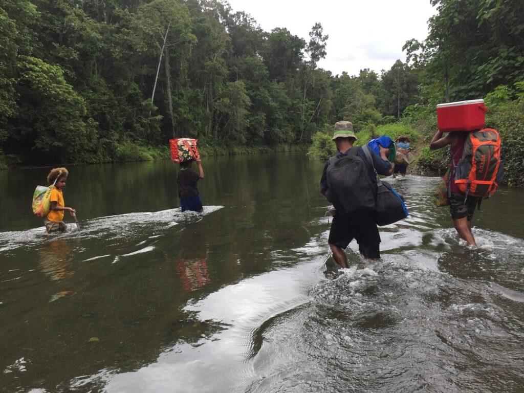 The team crossing rivers carrying essential supplies to remote communities in the rainforest. 